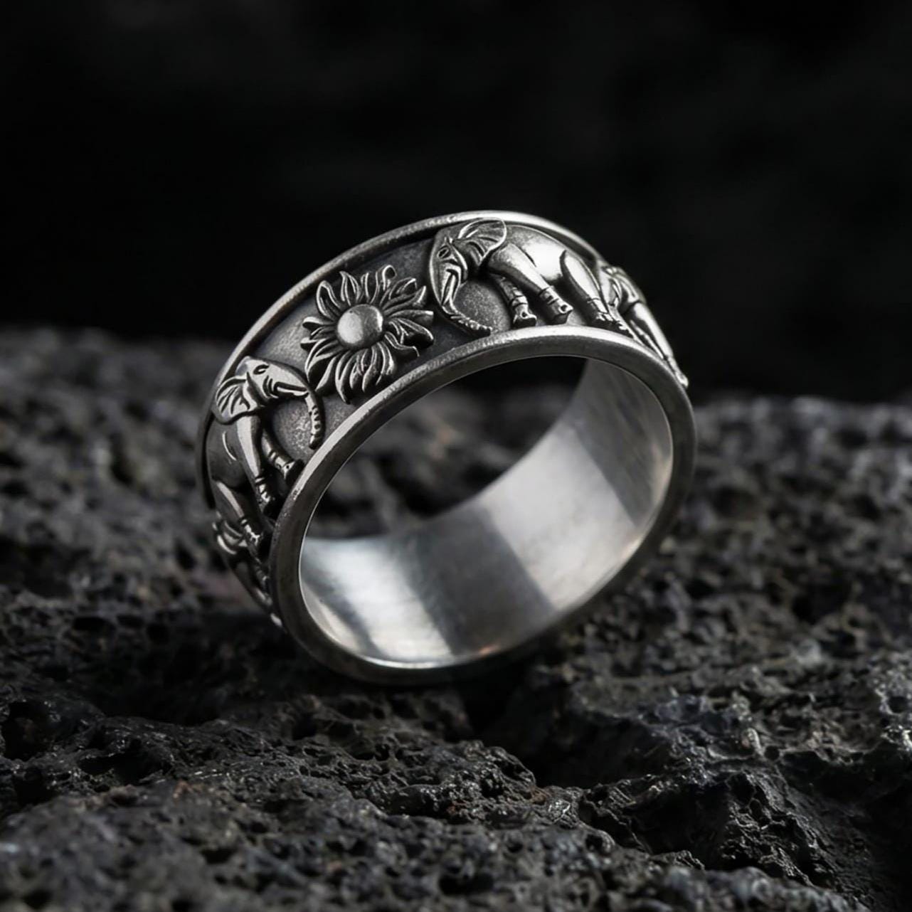 Oxidized geometric faceted band ring photographed on volcanic rock with sharp pyramid-cut texture and industrial masculine finish