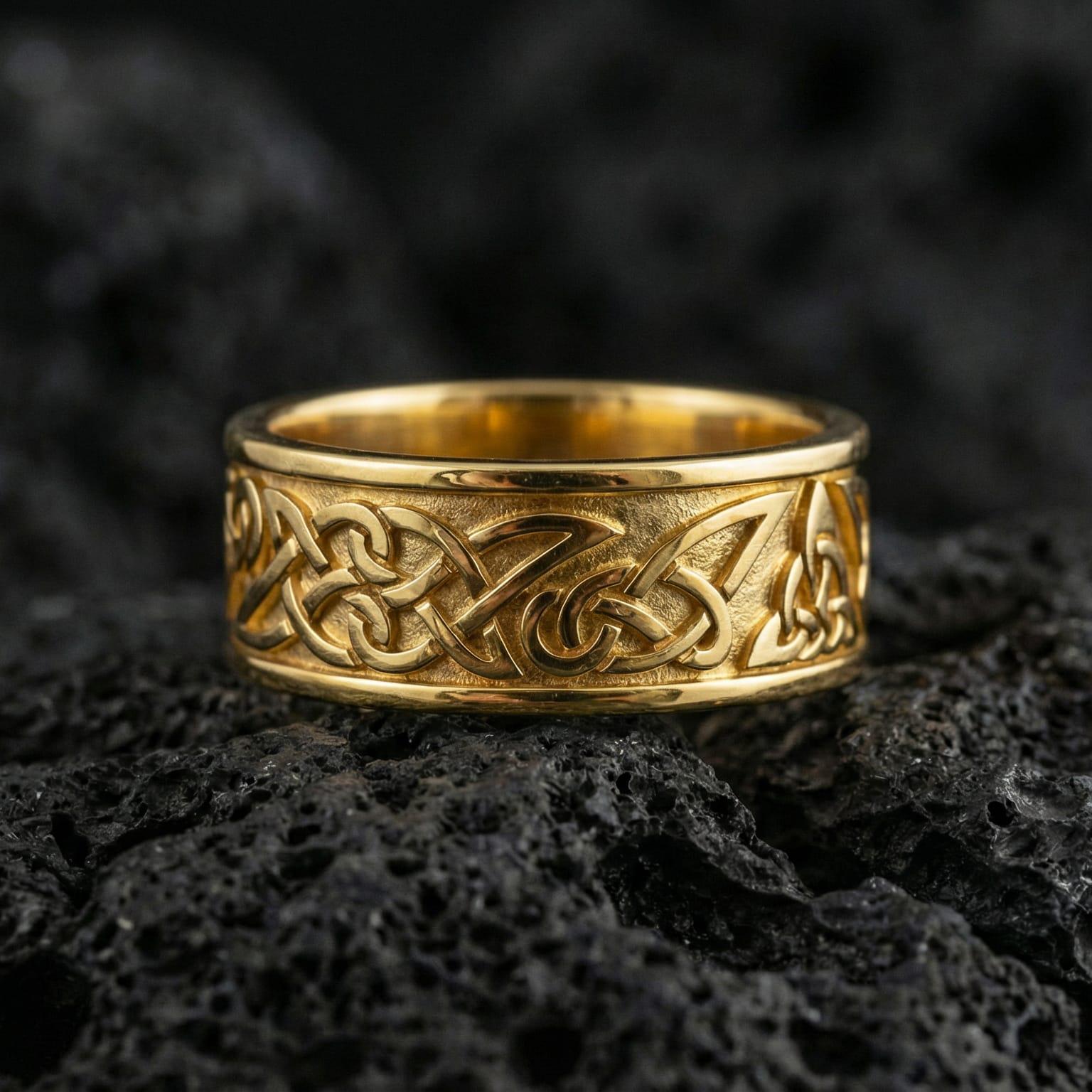 Gold plated Celtic braid ring showcased on volcanic rock with raised knotwork texture for a bold heritage statement wedding band