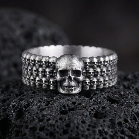 Oxidized faceted geometric band ring photographed on volcanic rock with sharp prism edges and matte industrial finish