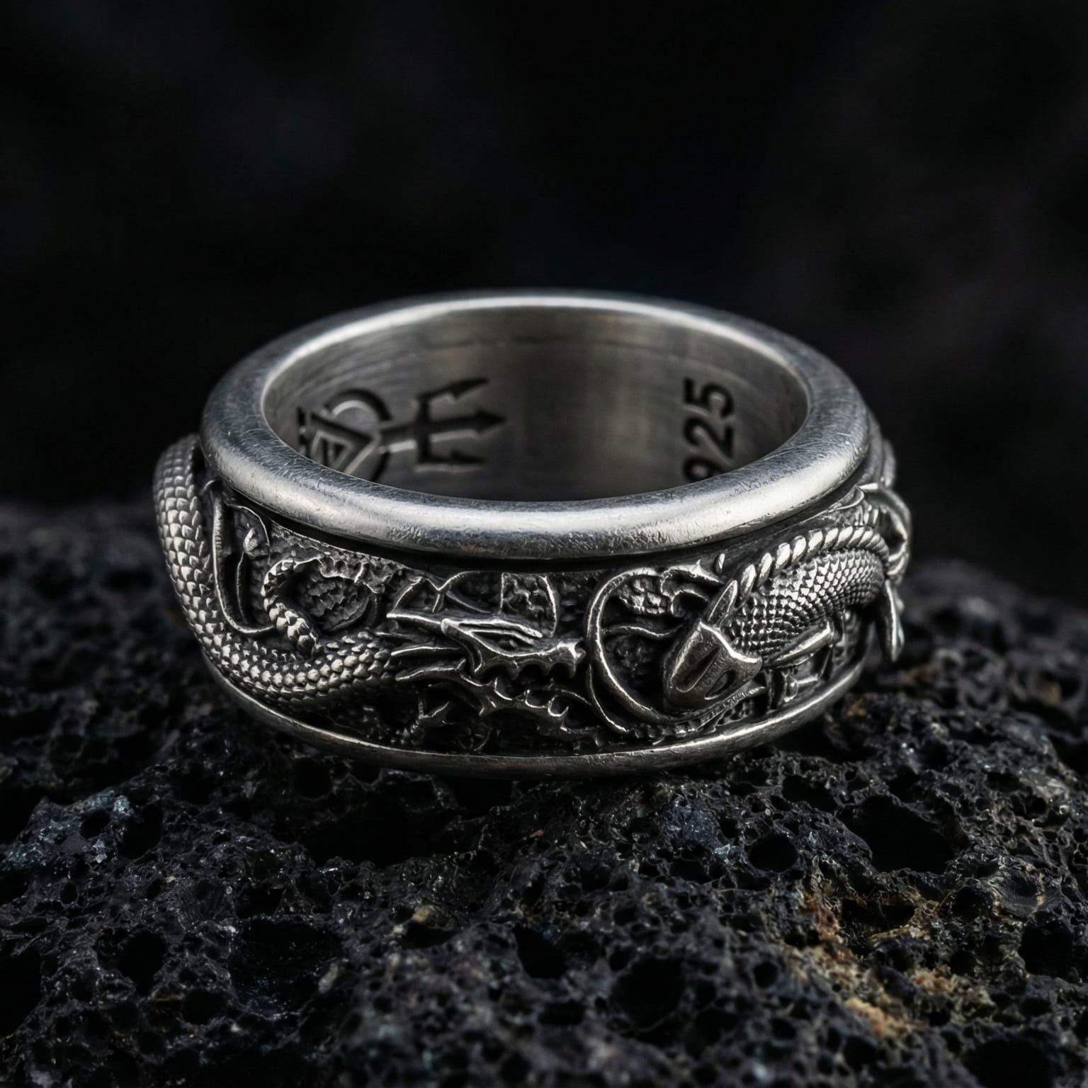 Oxidized spinning dragon and carp fish ring photographed on volcanic rock featuring high-relief oriental myth texture and rotating band design