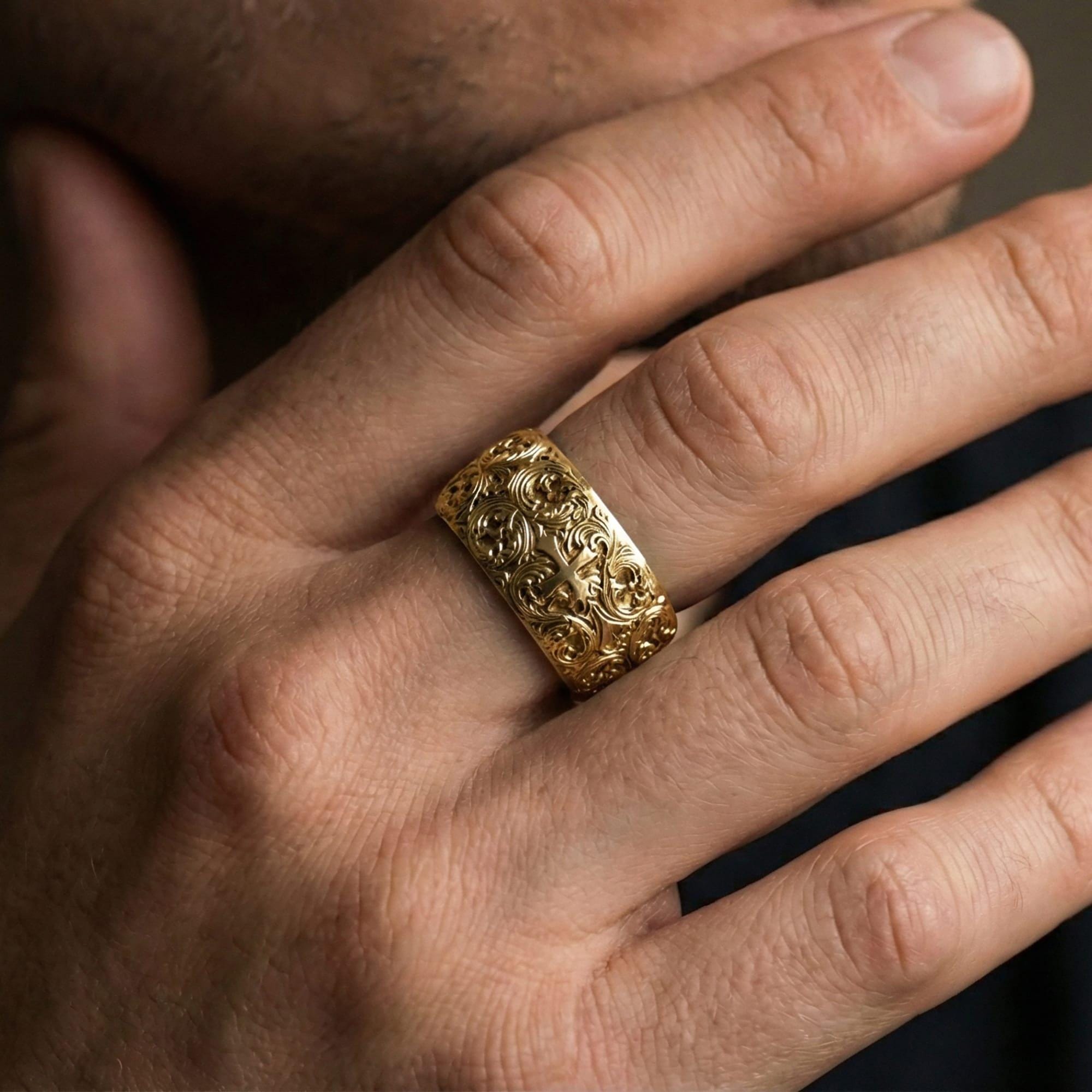 Gold plated ornate cross band ring worn on a finger, lifestyle wear photo emphasizing luxurious gold tone and high-relief filigree presence.