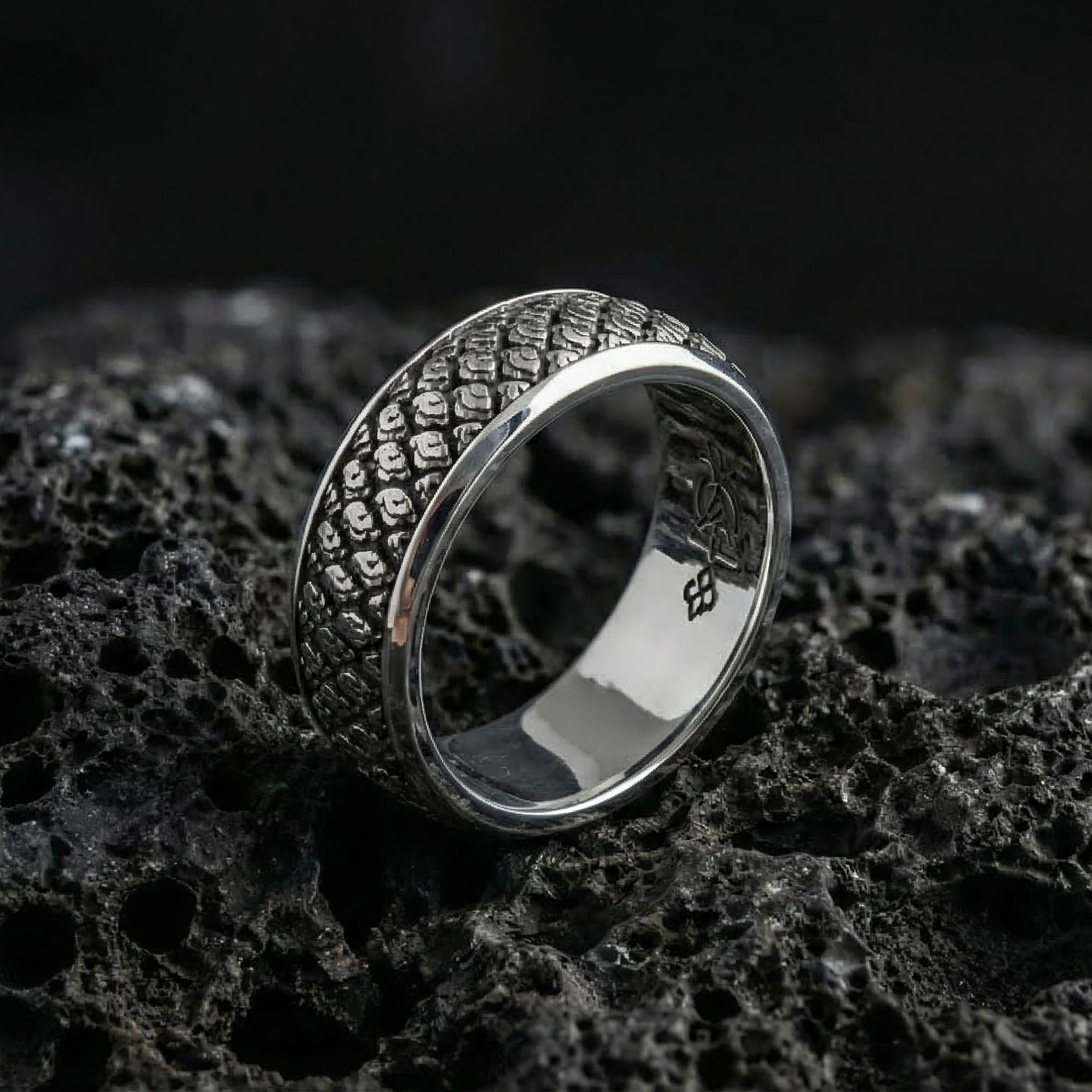 Polished silver Japanese cloud design wedding band displayed on volcanic stone, highlighting crisp scrollwork depth and clean reflective edges