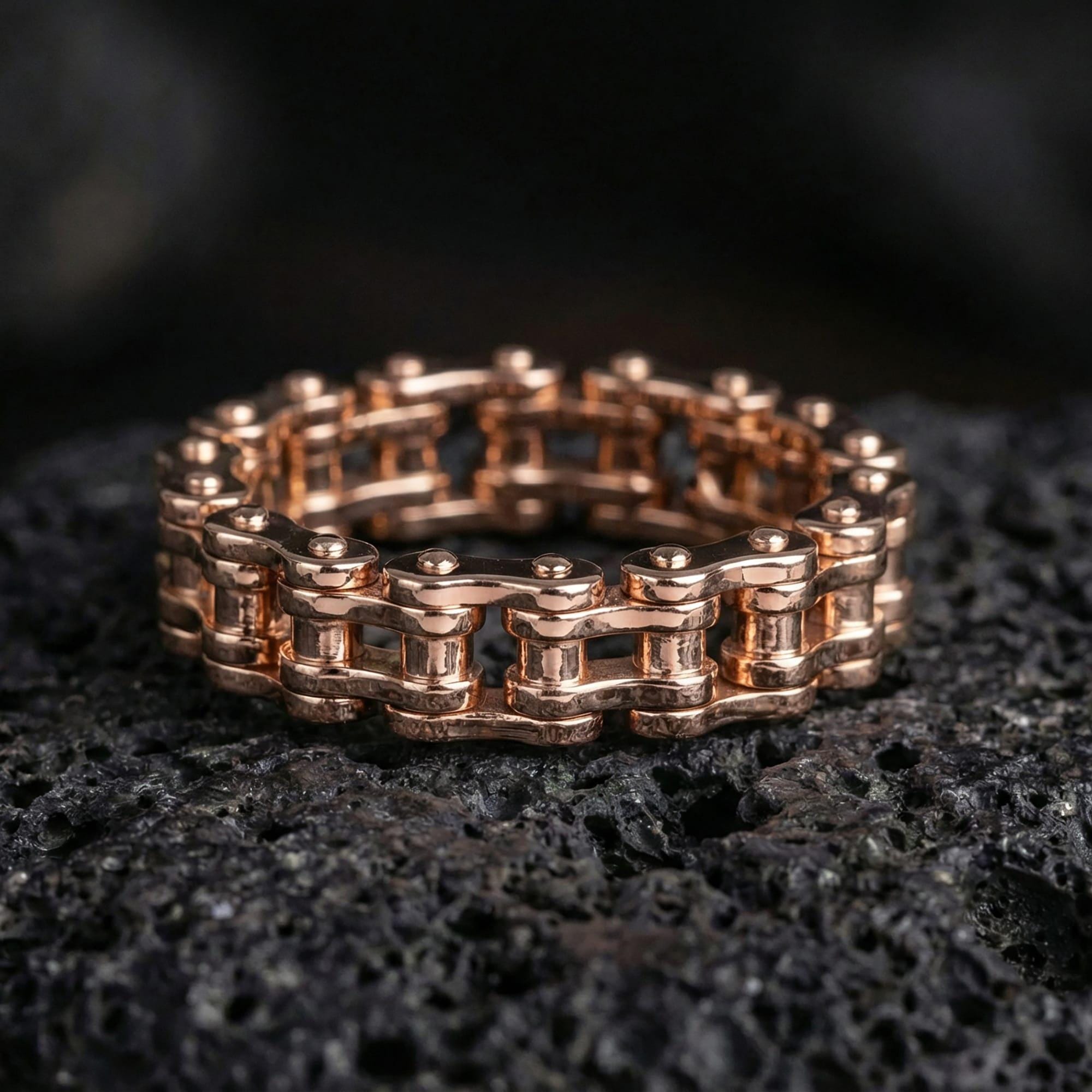 Rose gold plated steampunk chain wheel ring presented on volcanic rock surface with premium workshop aesthetic and refined industrial finish