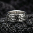 Load image into Gallery viewer, Polished silver wave engraved wedding band displayed on volcanic stone background, highlighting crisp scrollwork lines and clean reflective edges
