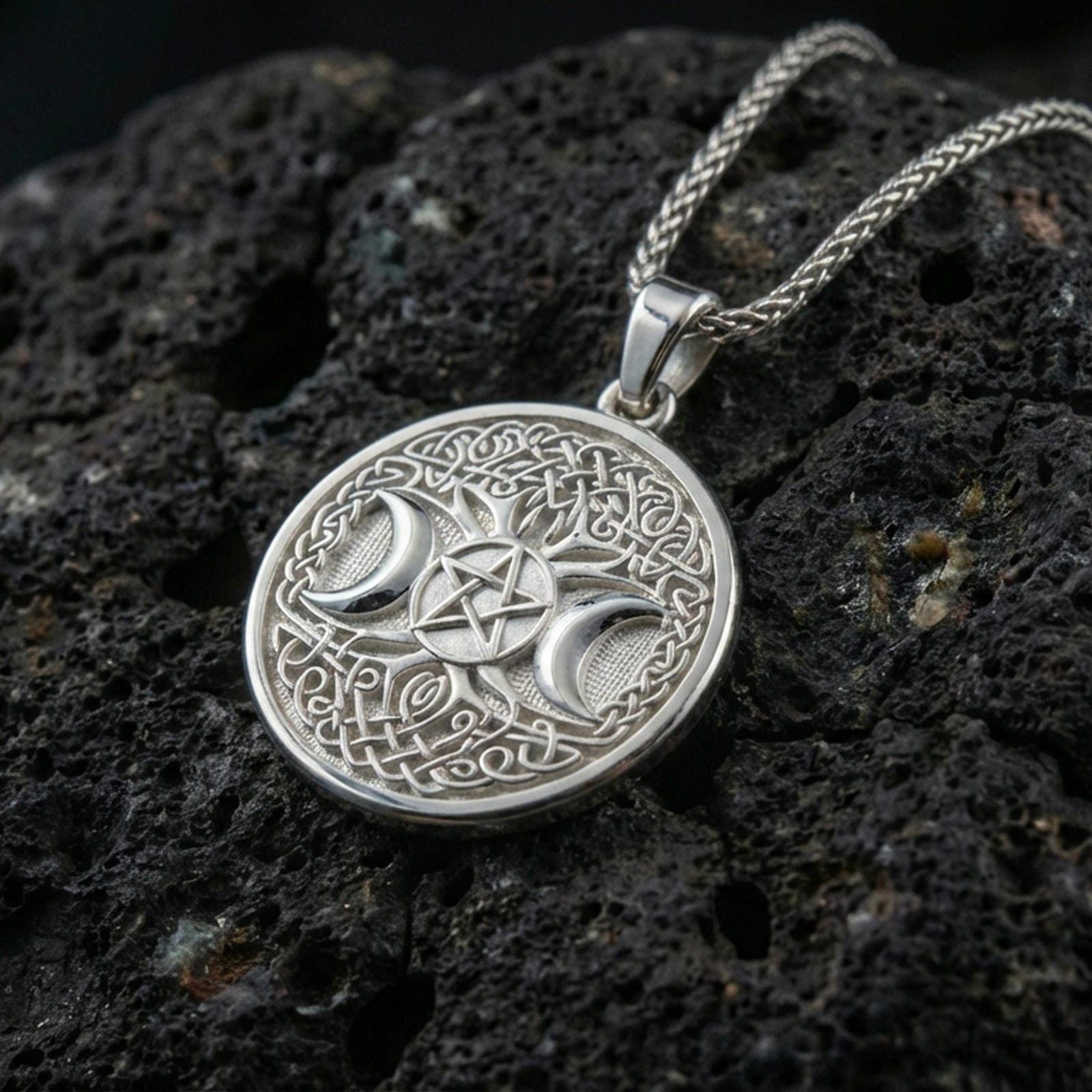 Polished silver triple moon pentagram necklace on porous volcanic stone, detailed Celtic knotwork medallion with bail