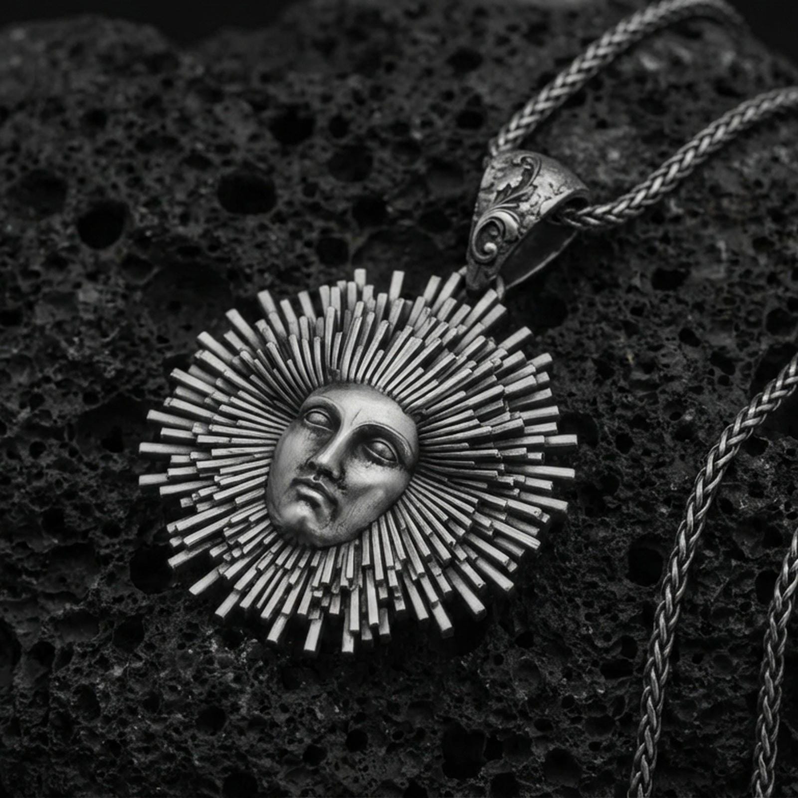 Oxidized 925 sterling silver Helios sun pendant on volcanic rock, radiant sunburst rays with face relief and braided chain