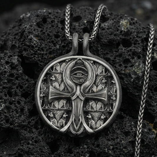 Oxidized 925 sterling silver ankh pendant on volcanic rock, Eye of Providence medallion with Egyptian symbolism and ornate background pattern