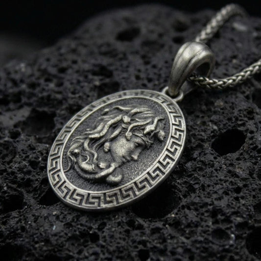 Oxidized 925 sterling silver Medusa coin pendant on volcanic rock, Greek key border medallion with raised goddess profile relief