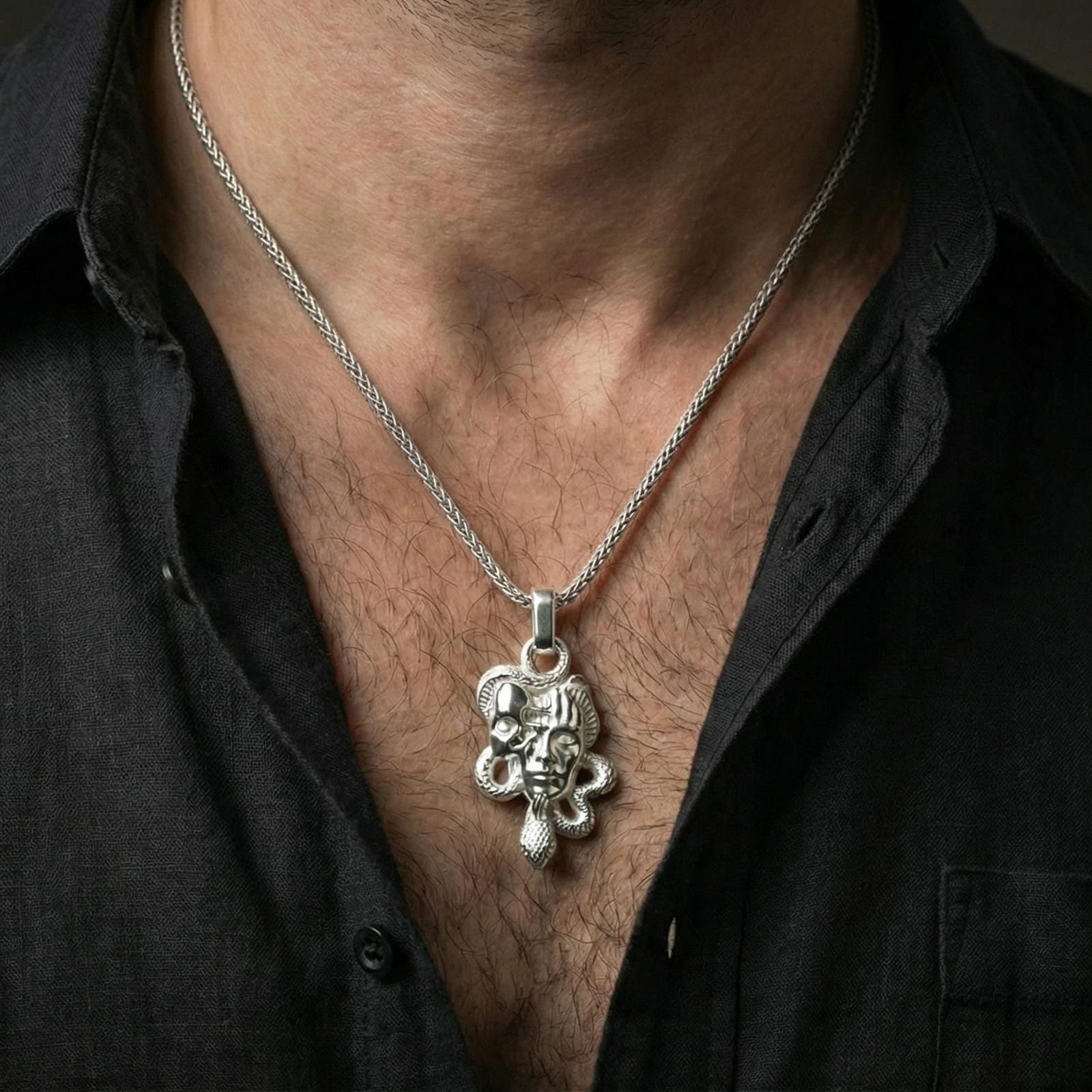 Polished silver Medusa skull necklace worn on neck, serpent pendant with sculpted face relief and bold statement style