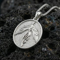 Load image into Gallery viewer, Polished silver phoenix medallion necklace on porous volcanic stone, flying bird pendant with crisp feather detailing
