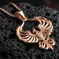 Load image into Gallery viewer, Rose gold plated phoenix necklace on dark volcanic stone, elegant rising phoenix pendant with detailed feather relief
