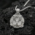 Load image into Gallery viewer, Polished silver yggdrasil pendant on porous volcanic stone, detailed tree of life relief with celtic knot border
