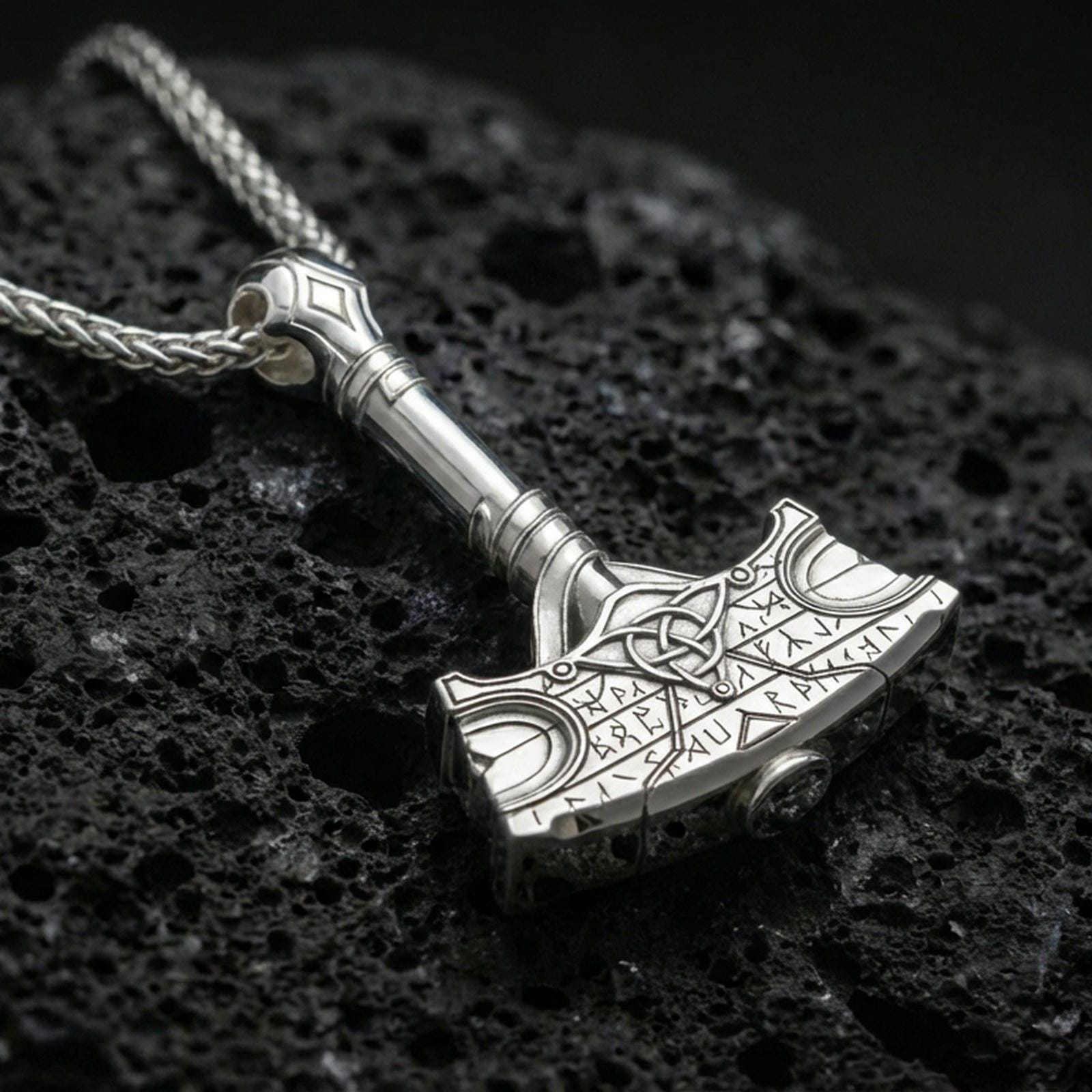 Polished silver Thor hammer necklace on porous volcanic stone, Mjolnir pendant with Celtic knot detail and runic border