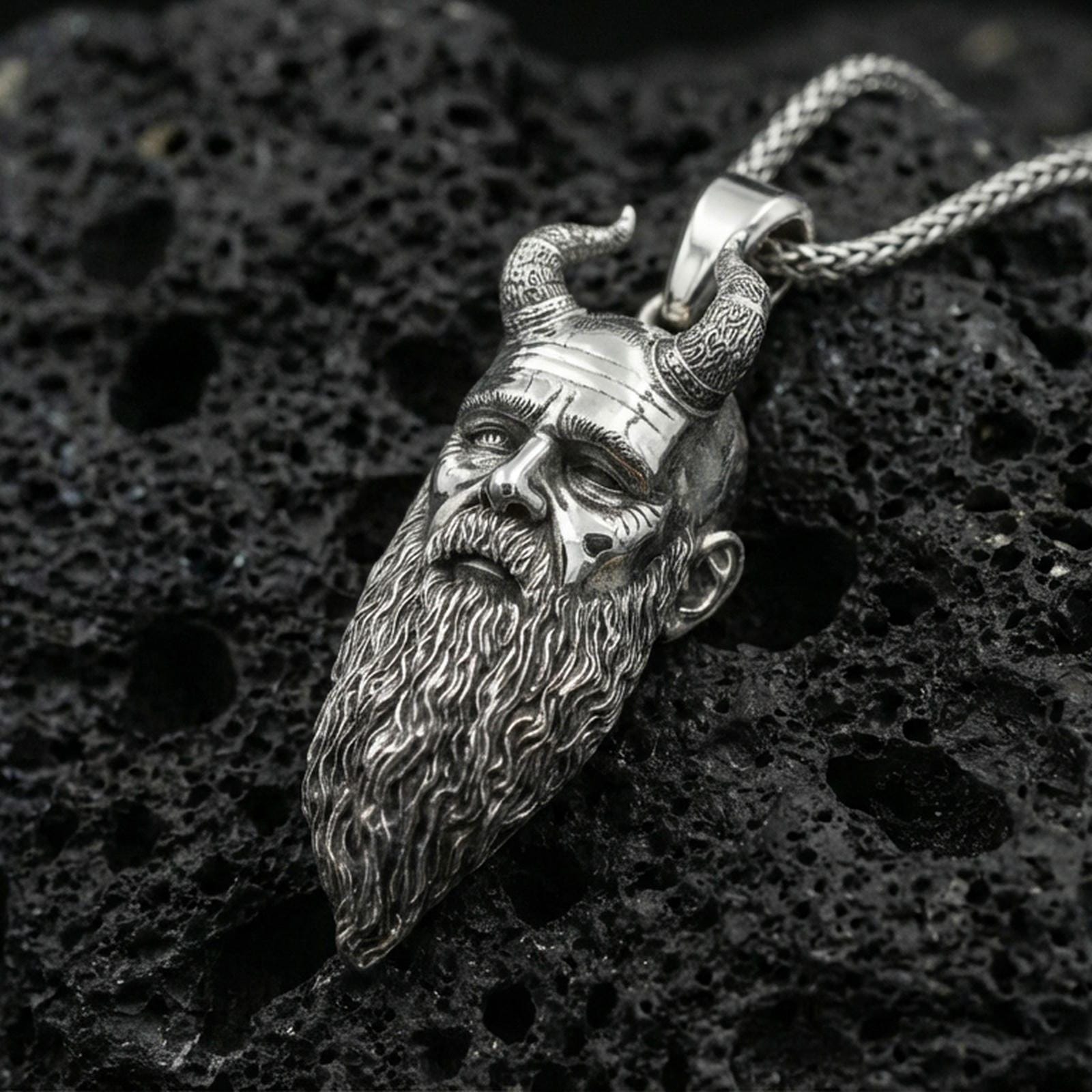 Polished silver Mimir head necklace on porous volcanic stone, detailed Viking face pendant with carved horn accents