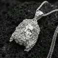Load image into Gallery viewer, Polished silver deity head pendant on volcanic rock, high-contrast texture background, close-up craftsmanship detail
