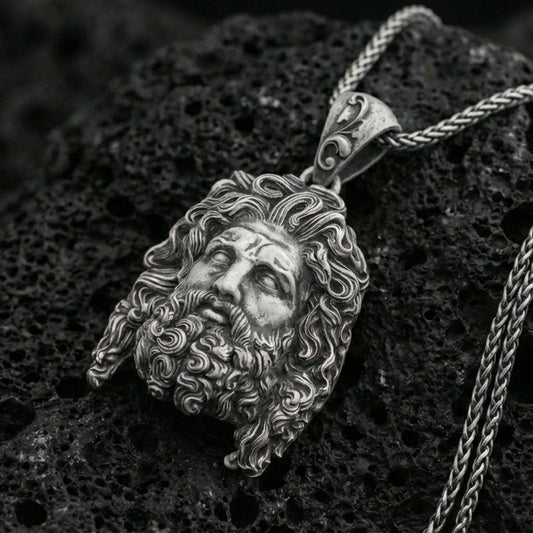 Oxidized sterling silver deity head pendant on volcanic rock, detailed sculpted hair and beard, macro studio shot