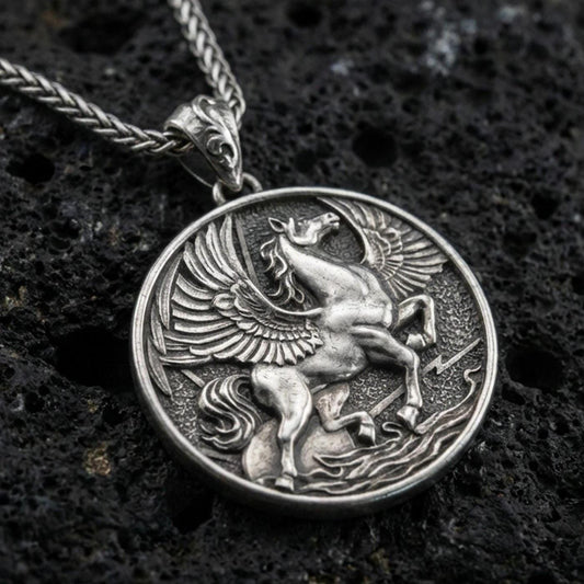 Oxidized sterling silver winged Pegasus medallion pendant on volcanic rock, high-relief flying horse design, macro shot