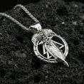 Load image into Gallery viewer, Polished silver raven and spear pendant on volcanic rock, sharp geometric rune-like frame detail, close-up studio lighting
