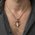 Load image into Gallery viewer, Rose gold plated raven and spear pendant necklace worn on neck, lifestyle wear shot, warm plating tone and sculpted depth

