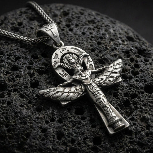 Oxidized sterling silver Egyptian winged ankh cross pendant on volcanic rock, engraved hieroglyph details, macro studio shot