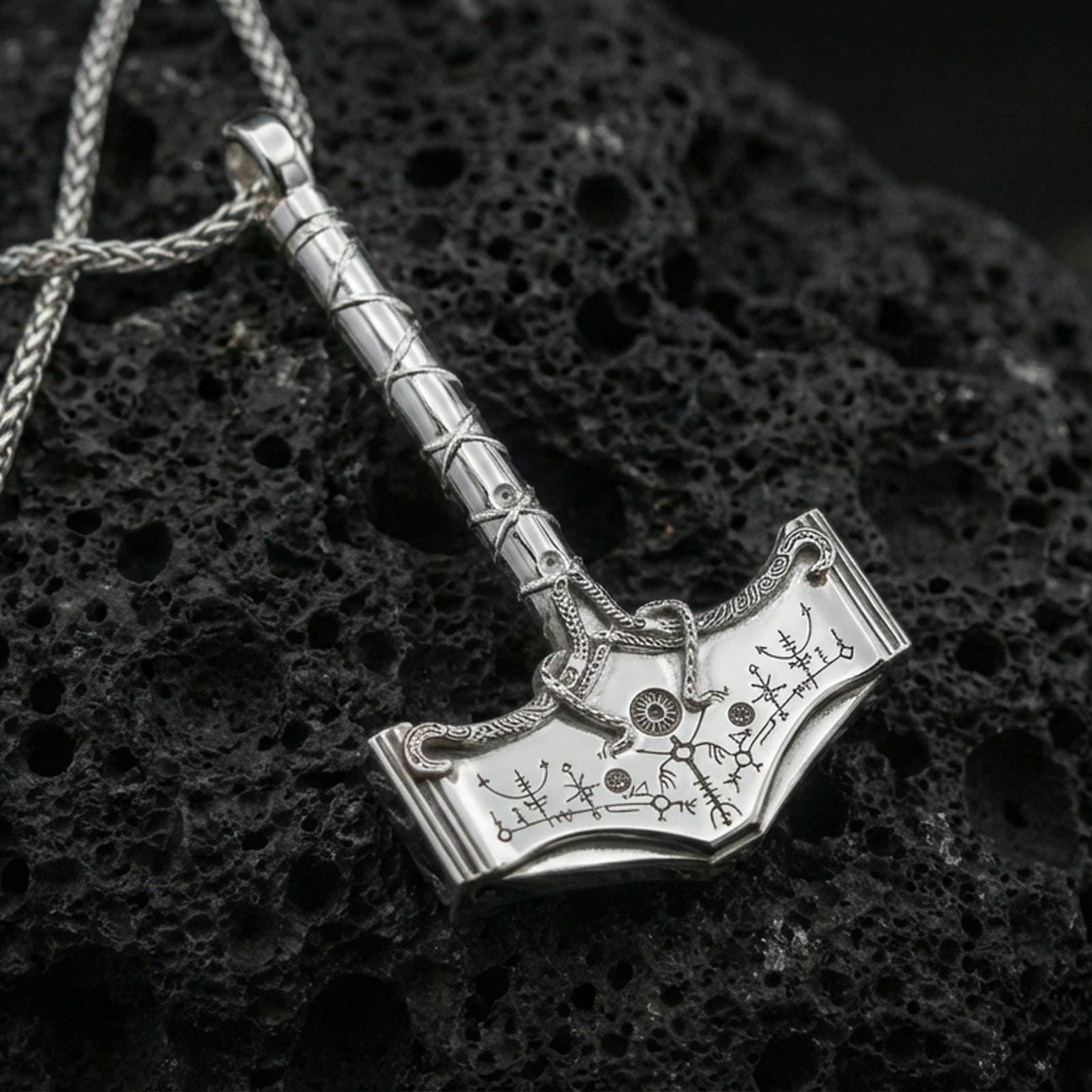 Polished silver Thor hammer necklace on volcanic rock, sharp etched rune symbols and clean hammered edges, close-up lighting
