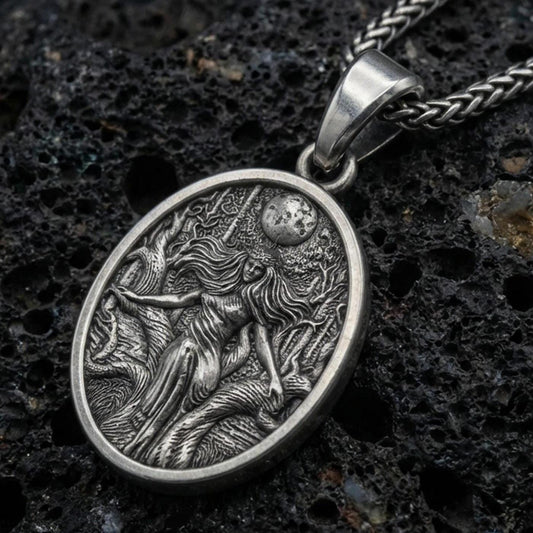 Oxidized sterling silver Hela pendant on volcanic rock, Norse mythology goddess relief with moon detail, macro studio shot