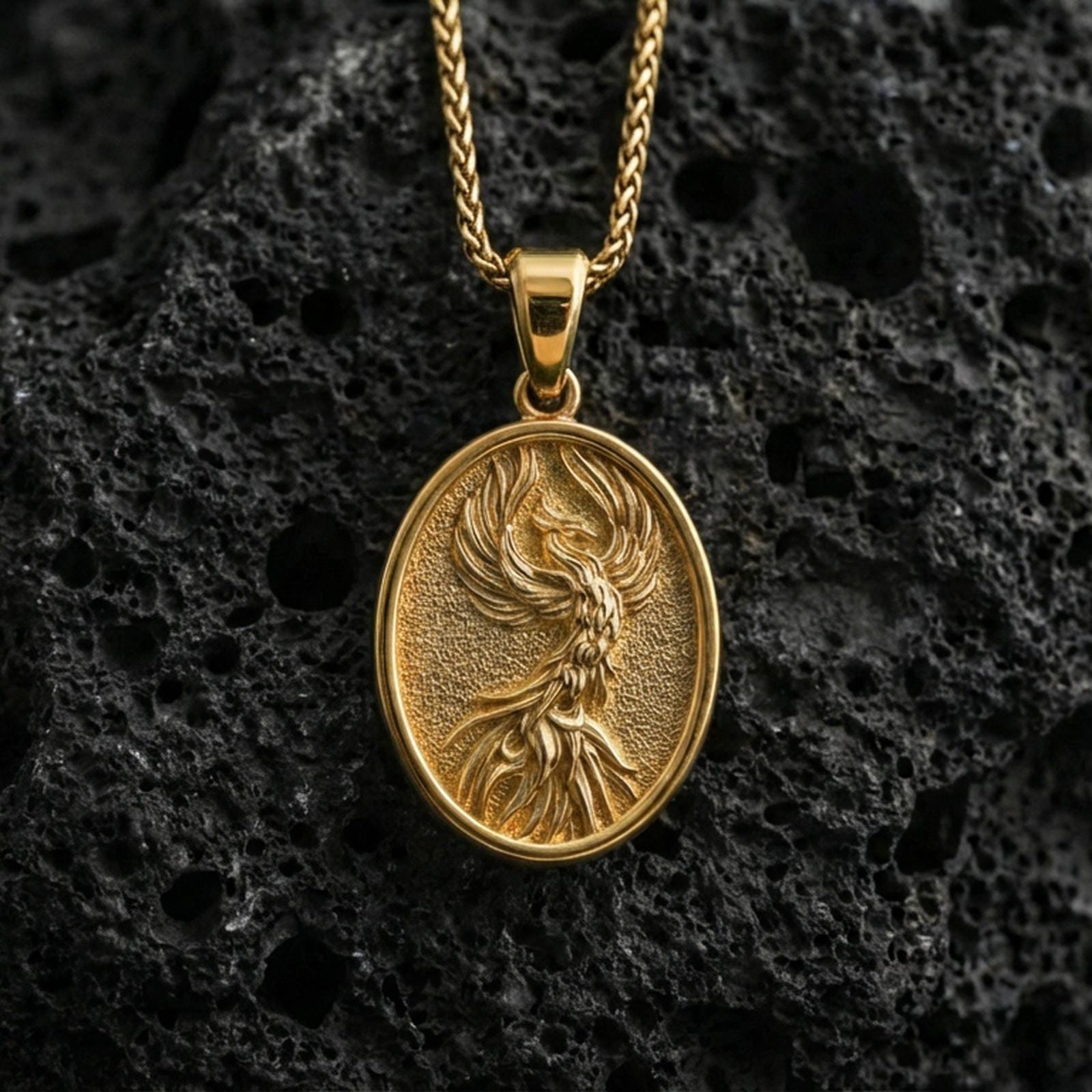Gold plated phoenix bird pendant on volcanic rock, premium studio lighting, mythic rebirth talisman design