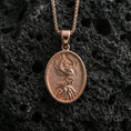 Load image into Gallery viewer, Rose gold plated phoenix medallion pendant on volcanic rock, textured lava stone background, detailed feather engraving
