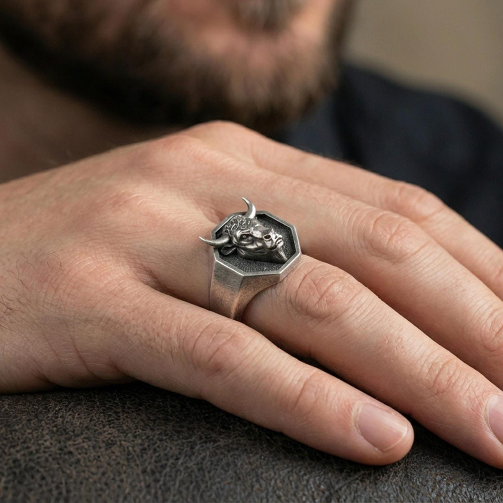 Oxidized bull head signet ring worn on finger, lifestyle close-up, octagonal face centered with rugged masculine styling