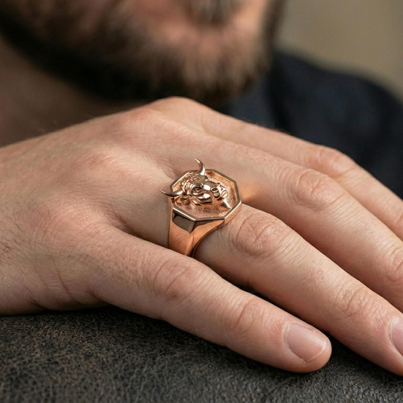 Rose gold plated bull head signet ring worn on finger, lifestyle wear shot, warm plating tone and sculpted depth