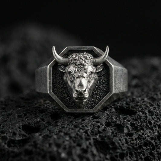 Oxidized sterling silver bull head signet ring on volcanic rock, octagonal face with high-relief horns, macro studio shot