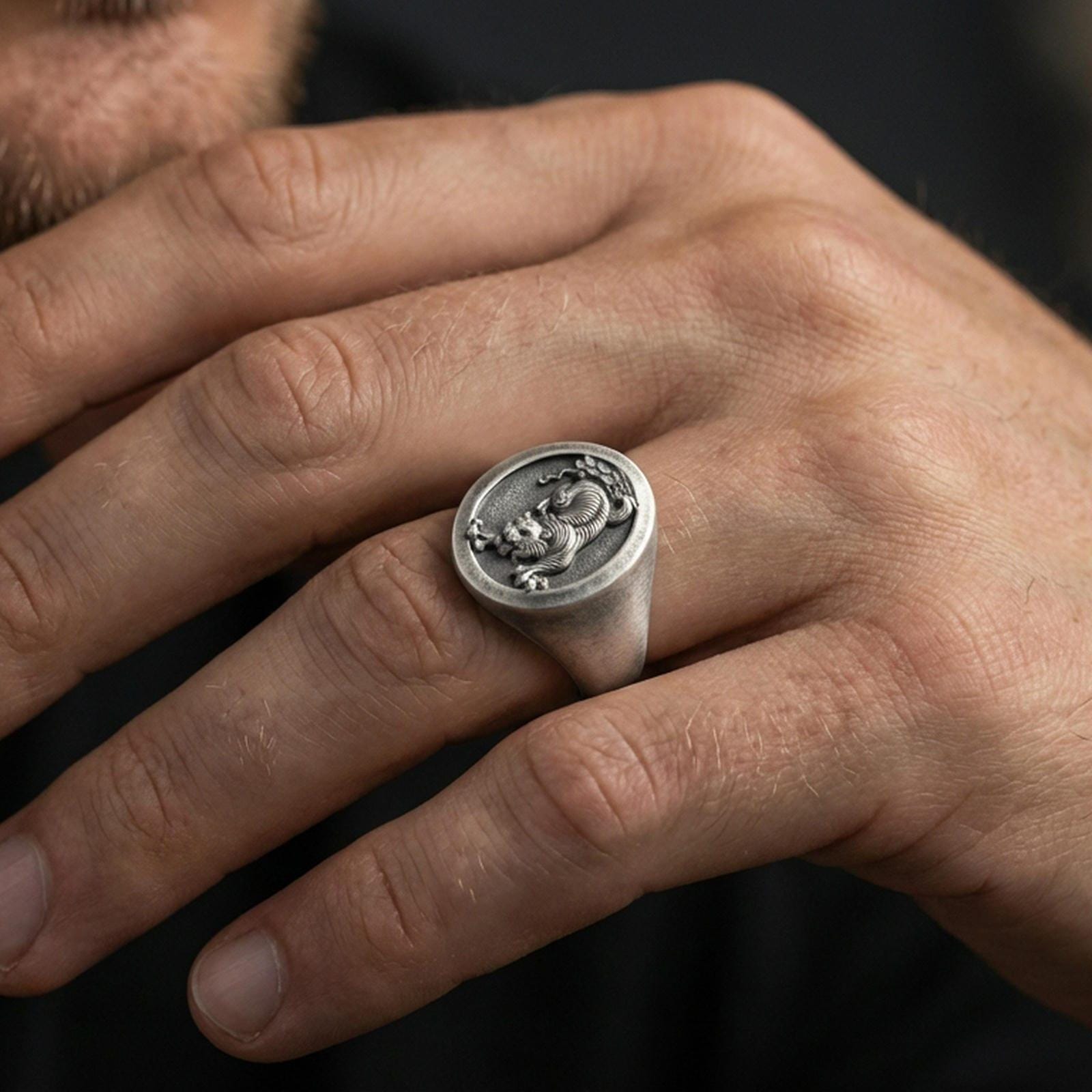 Oxidized Asian tiger signet ring worn on finger, lifestyle close-up, oval face centered with rugged masculine styling