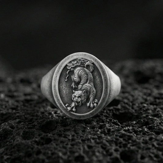 Oxidized sterling silver Asian tiger signet ring on volcanic rock, prowling tiger relief with textured background, macro shot