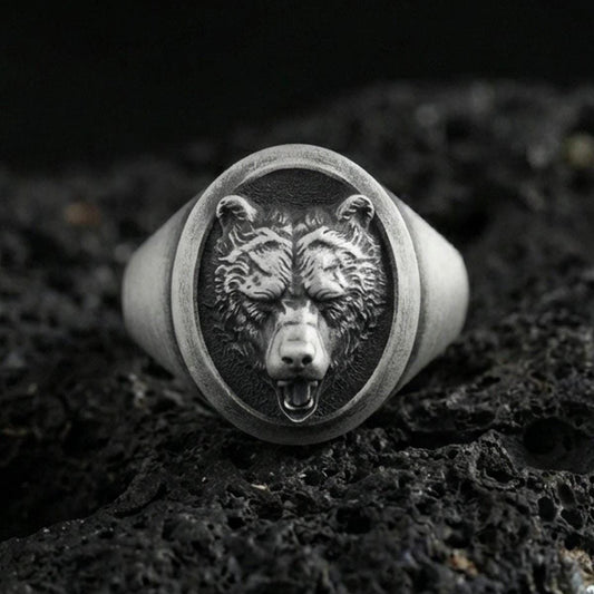 Oxidized sterling silver bear head signet ring on volcanic rock, detailed fur texture and open-mouth relief, macro studio shot