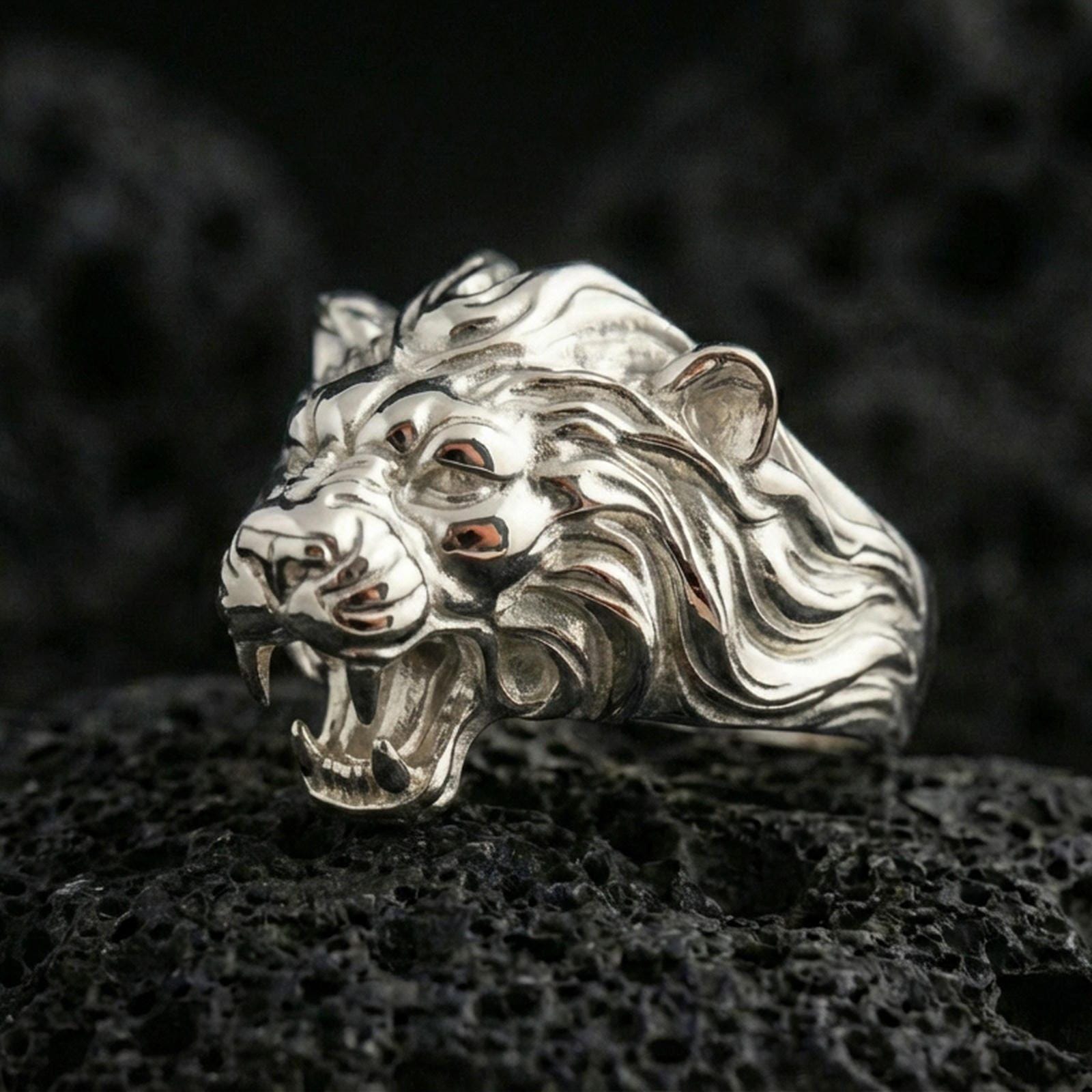 Polished silver angry lion king ring on volcanic rock, high-relief roaring lion face and flowing mane detail, sharp focus shot