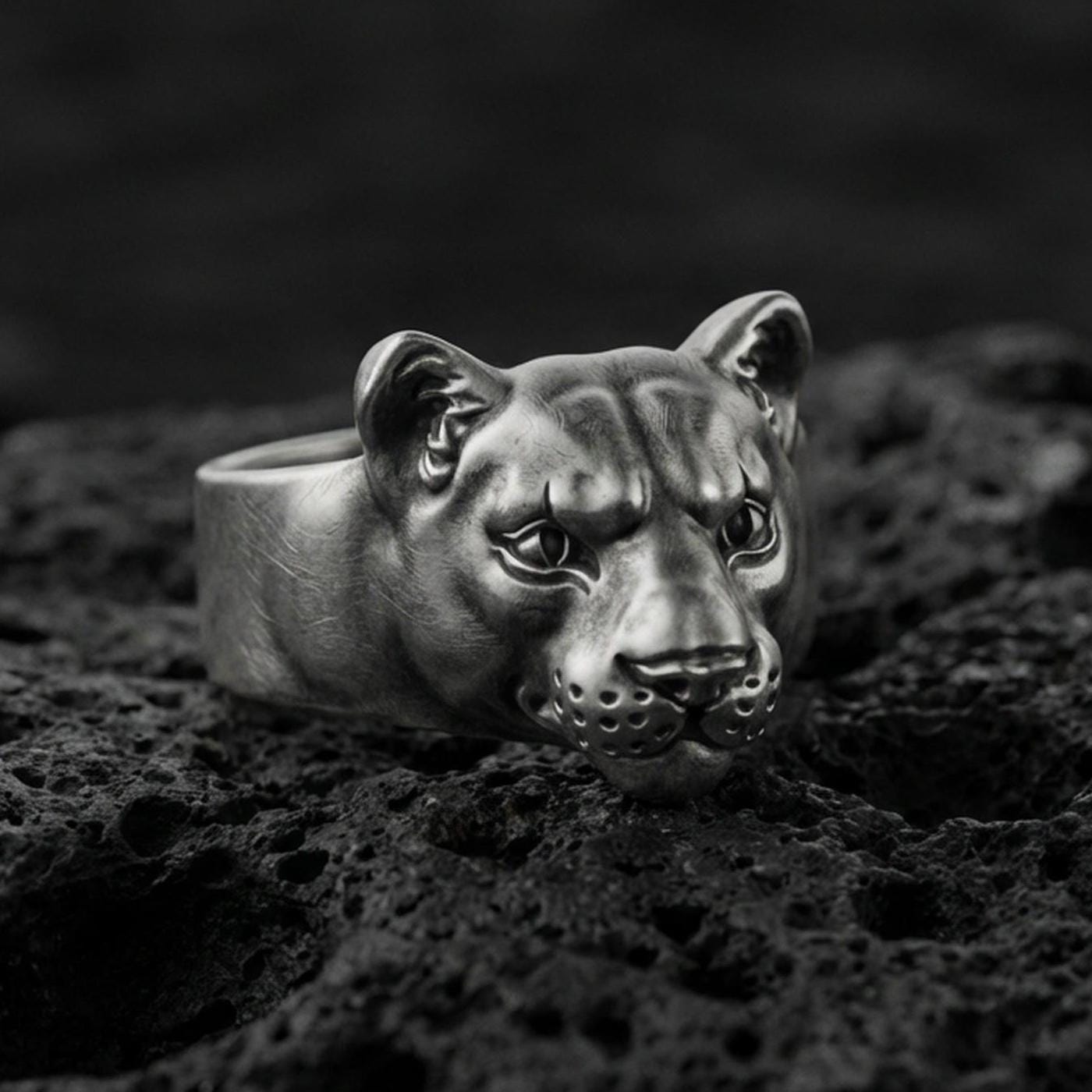 Oxidized sterling silver puma head ring on volcanic rock, smooth wild cat face with detailed eyes, macro product shot