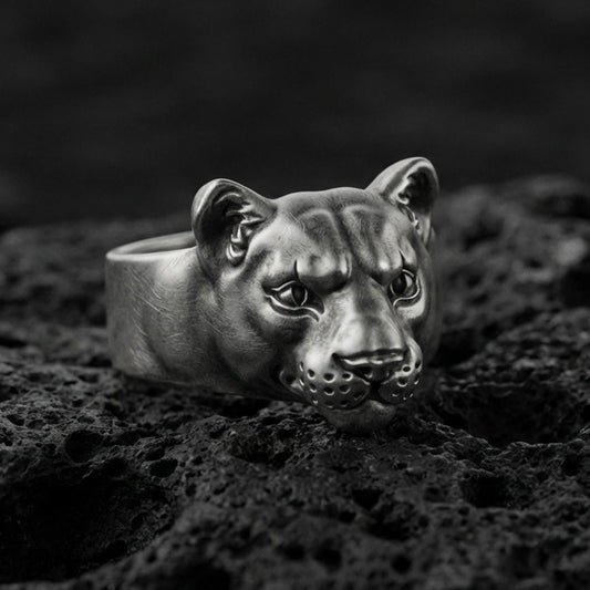 Oxidized sterling silver puma head ring on volcanic rock, smooth wild cat face with detailed eyes, macro product shot