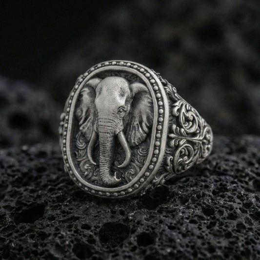 Oxidized sterling silver elephant signet ring on volcanic rock, detailed trunk and tusks with ornate engraved band, macro shot