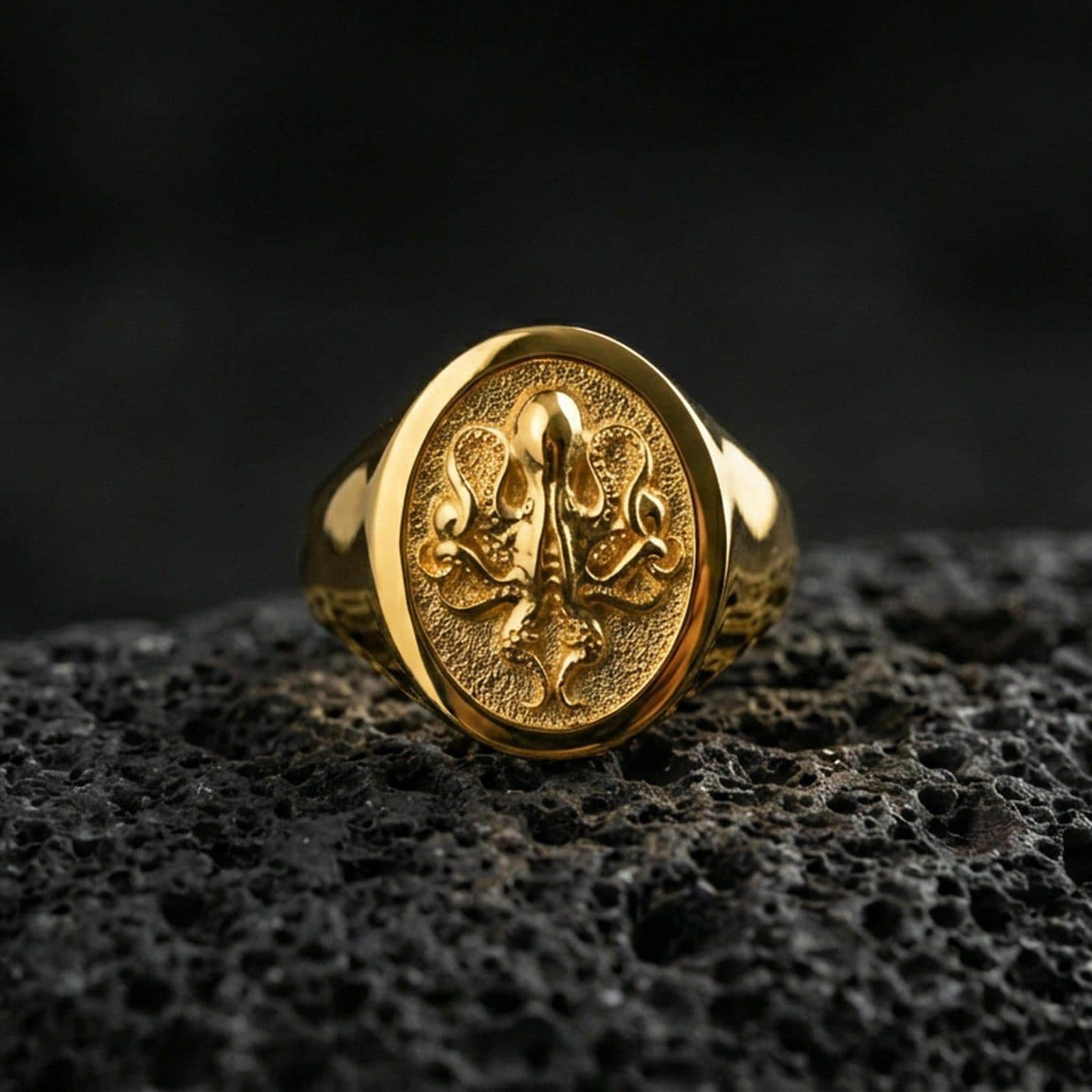 Gold plated octopus signet ring on volcanic rock, bold octopus symbol ring with textured recessed field and smooth bezel edge, premium macro lighting