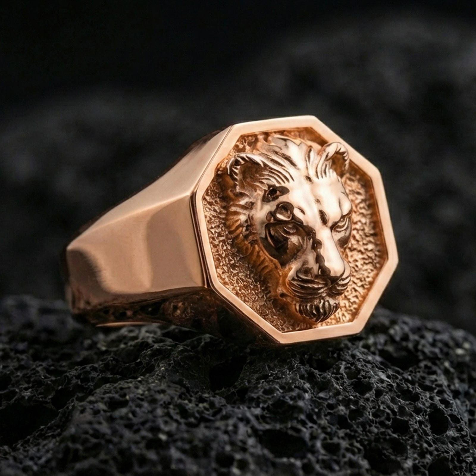 Rose gold plated lioness signet ring on volcanic rock, octagonal lioness crest ring with high-relief facial details and smooth bezel frame, luxury macro