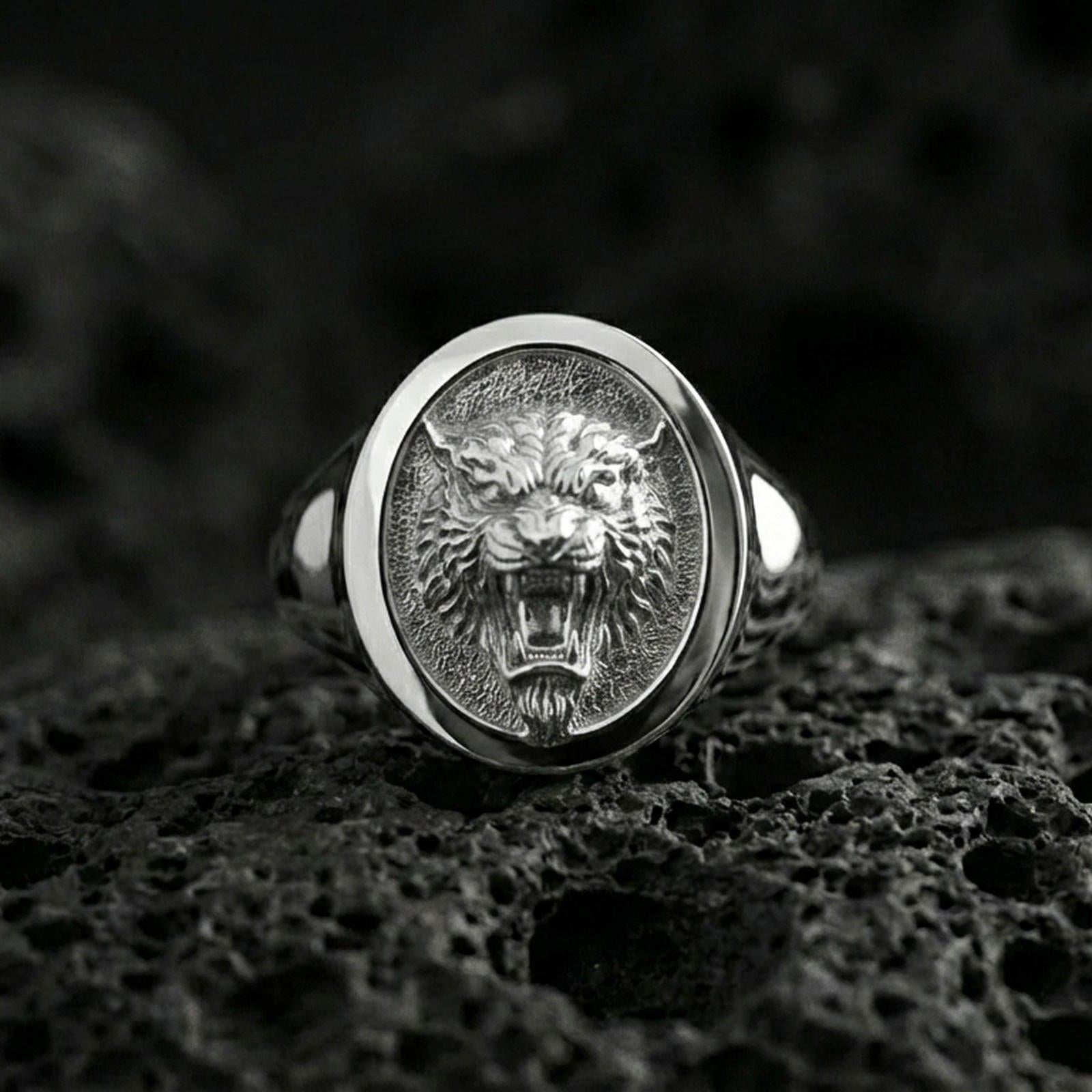Polished silver tiger signet ring on volcanic rock, oval bezel with detailed tiger portrait and clean smooth rim, close-up jewelry shot