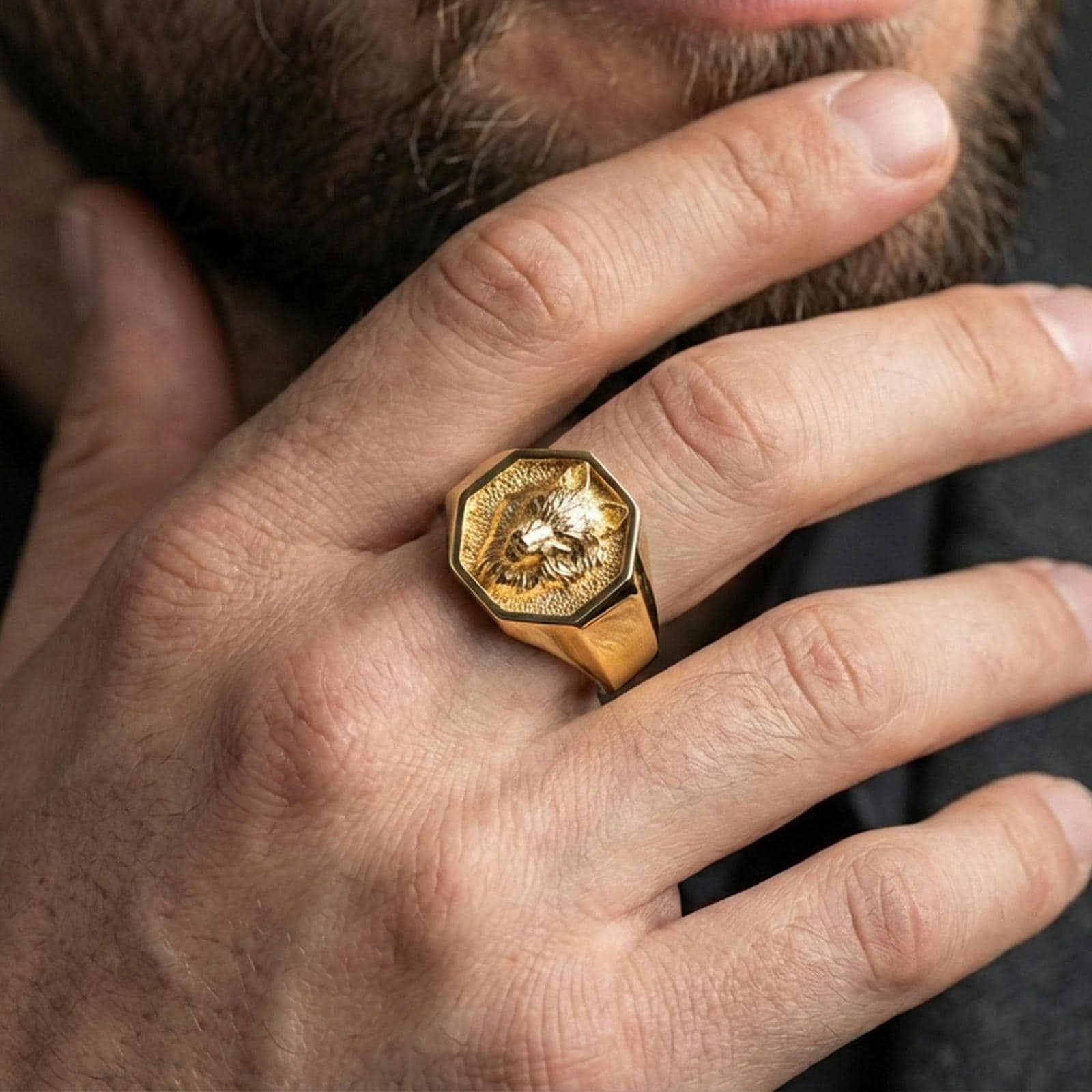 Gold plated wolf octagon signet ring worn on finger, premium lifestyle photo, statement wolf totem ring with detailed fur carving