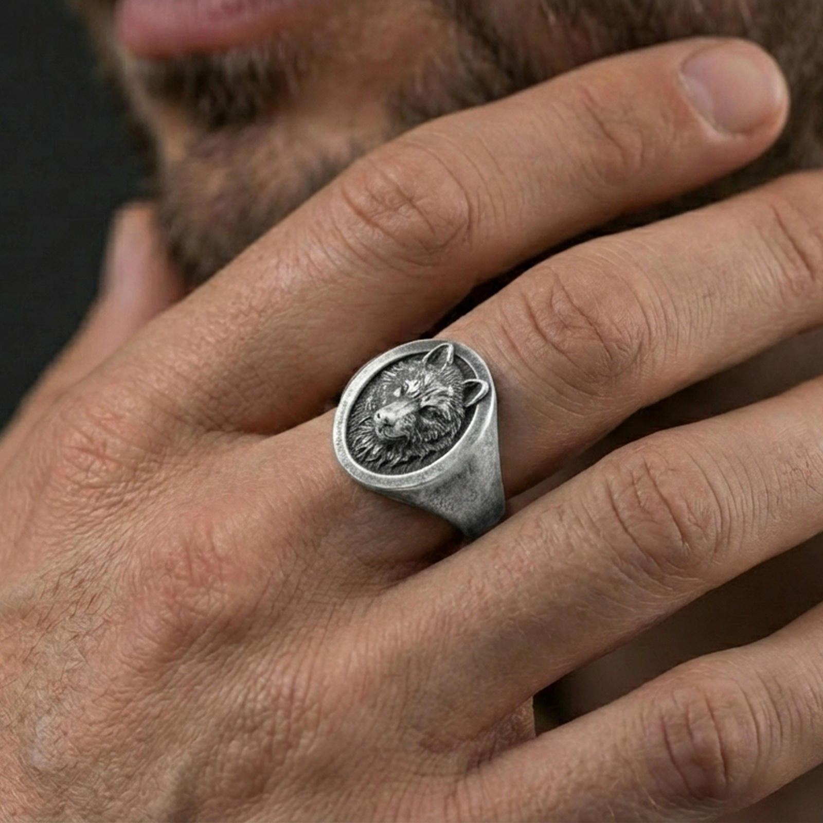 Oxidized oval wolf signet ring worn on finger, lifestyle close-up showing raised wolf head relief on smooth tapered band