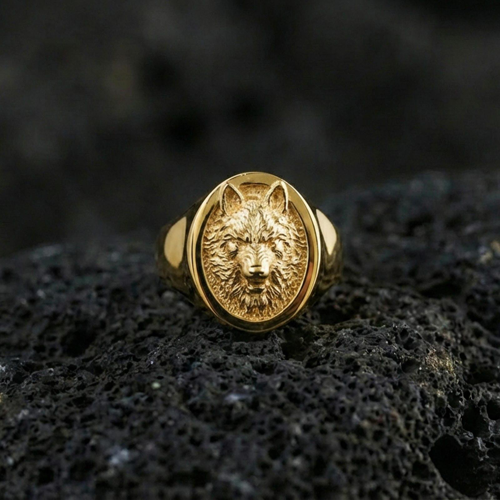 Gold plated wolf signet ring on volcanic rock, oval wolf head emblem with high-relief fur texture and deep contrast field, studio macro lighting