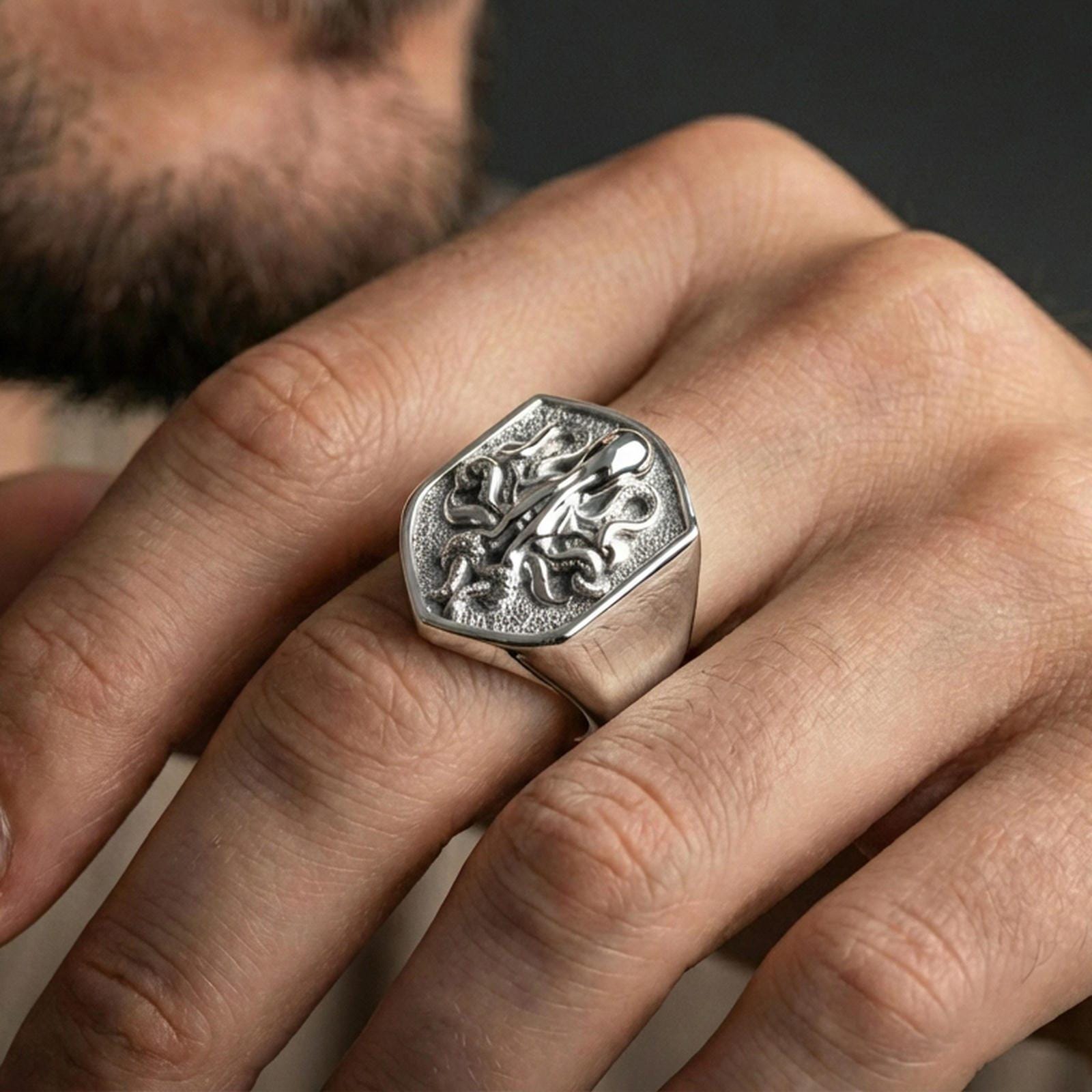 Polished silver shield octopus signet ring worn on finger, lifestyle hand shot highlighting crisp crest outline and high-relief tentacle details