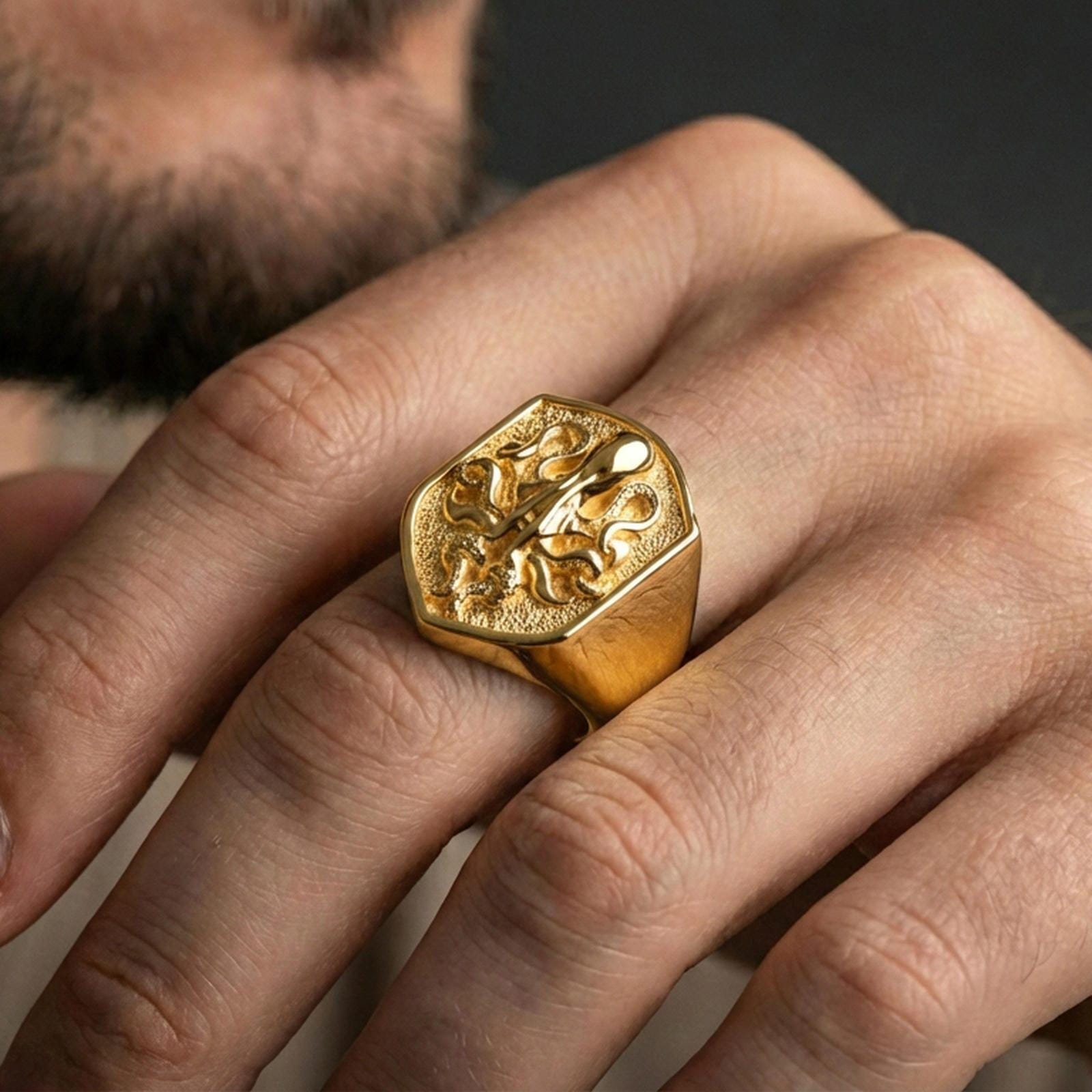 Gold plated shield octopus signet ring worn on finger, premium lifestyle wear photo featuring bold nautical octopus emblem and solid signet profile