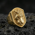 Load image into Gallery viewer, Gold plated tiger signet ring on volcanic rock, shield-shaped big cat emblem with sculpted tiger face and deep contrast texture, studio macro lighting
