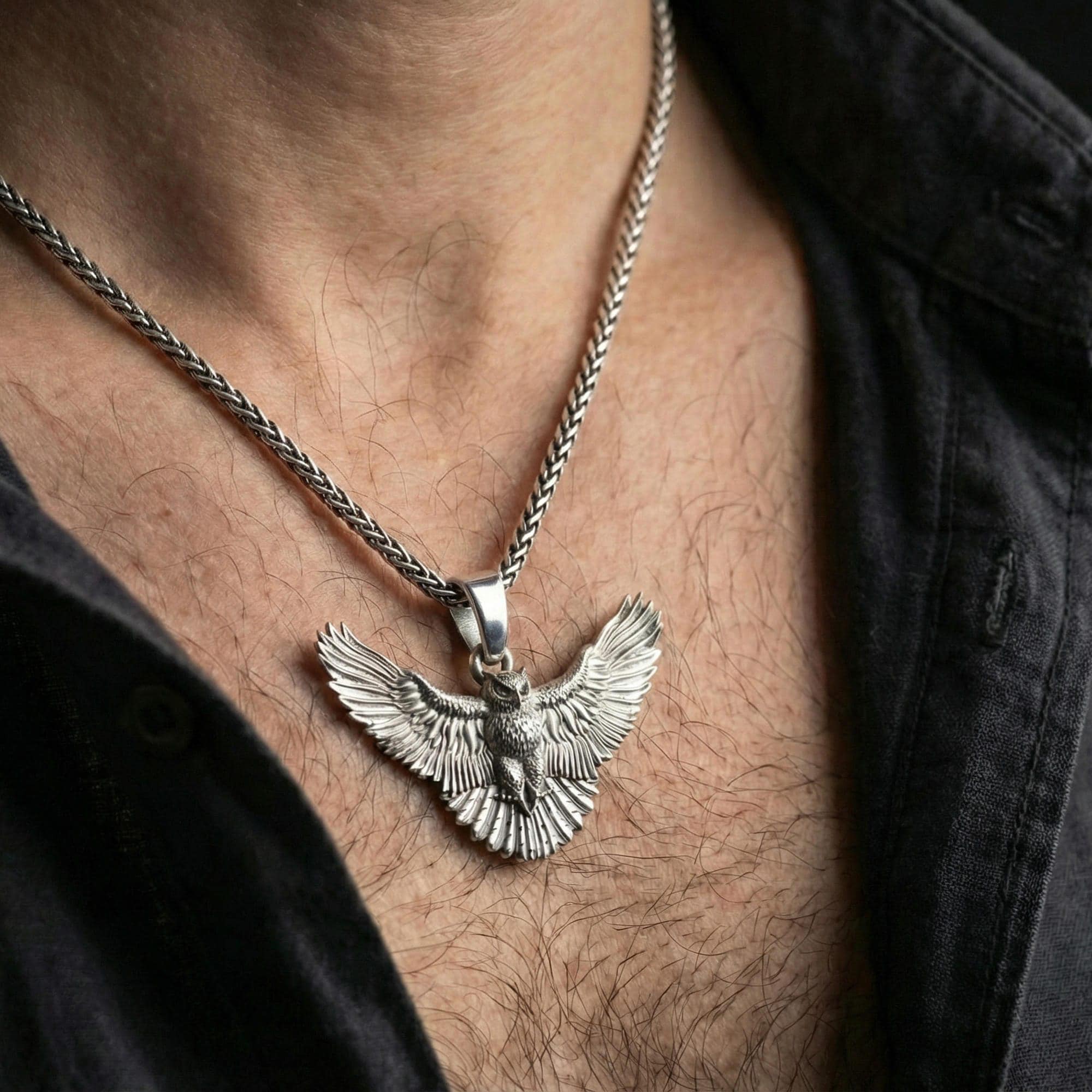 Polished silver owl pendant on braided chain worn on neck, natural lifestyle framing, detailed wings visible