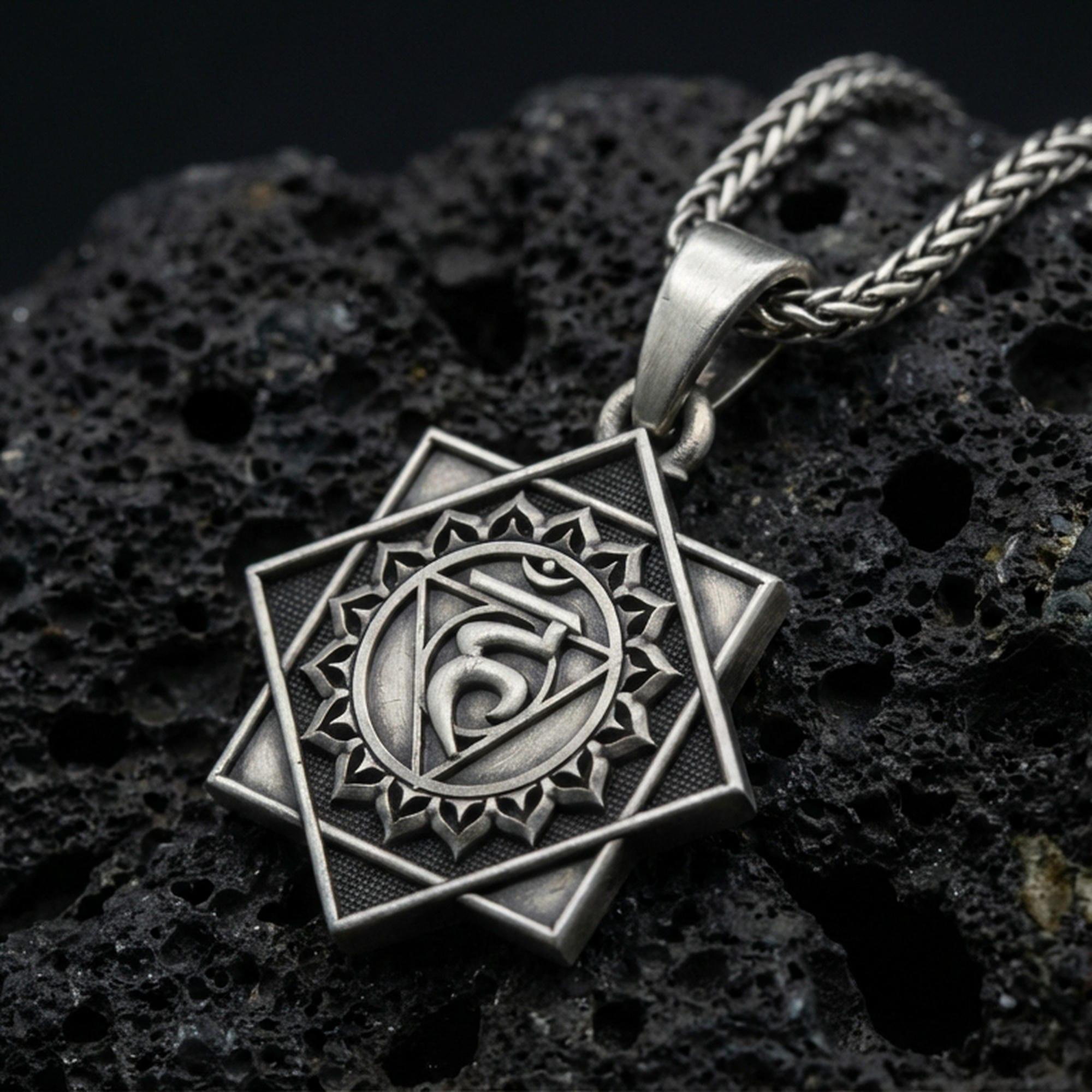 Oxidized Throat Chakra (Vishuddha) pendant on textured volcanic rock, macro close-up, geometric chakra symbol detail, premium studio lighting