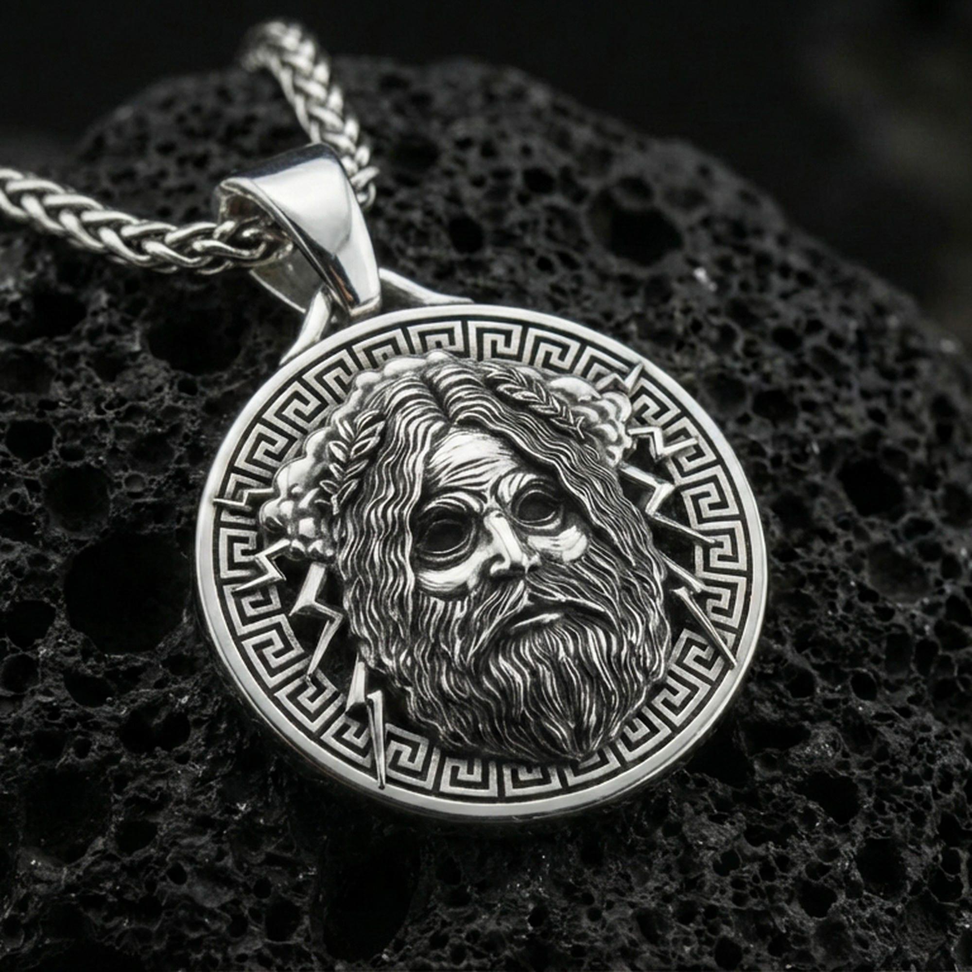 Polished silver Zeus necklace pendant on black volcanic stone background, crisp Zeus face relief and Greek key border, high-end product shot